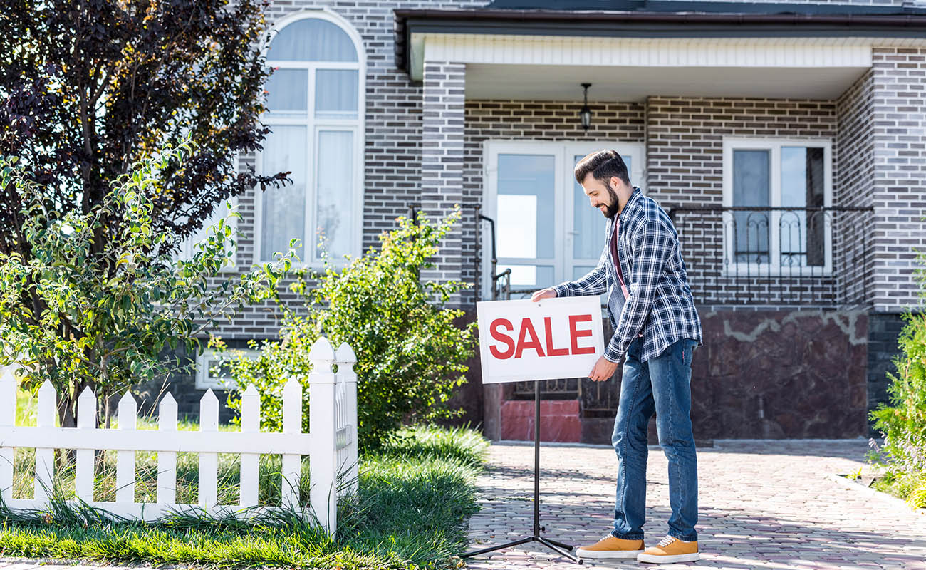 Man posting for sale sign.