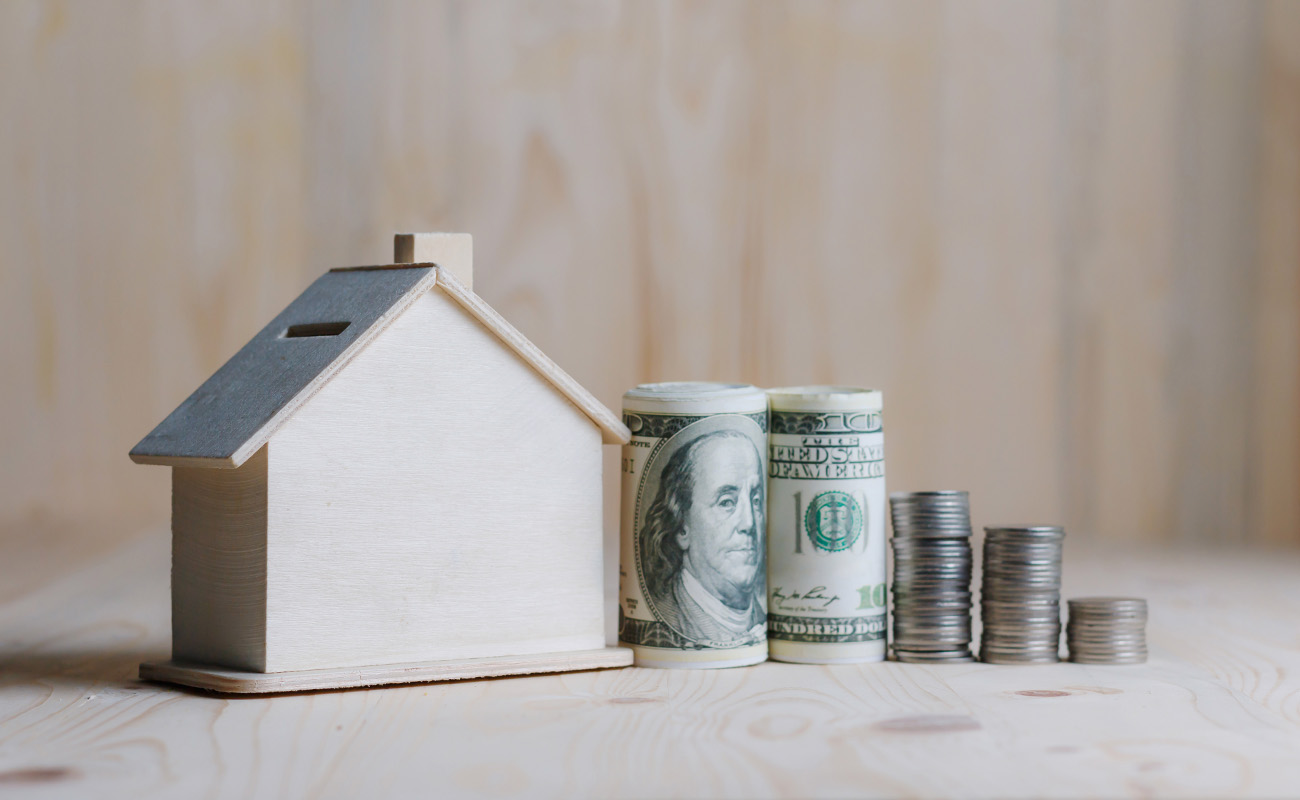 Wooden house with money beside it.